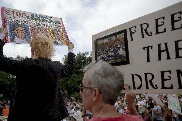 Heidi Turpin, left, dressed as President Donald Trump, holds up a sign next to her husband, Jim, during a protest against detaining migrant children, Thursday, July 4, 2019, in Austin, Texas. (Nick Wagner/Austin American-Statesman via AP)