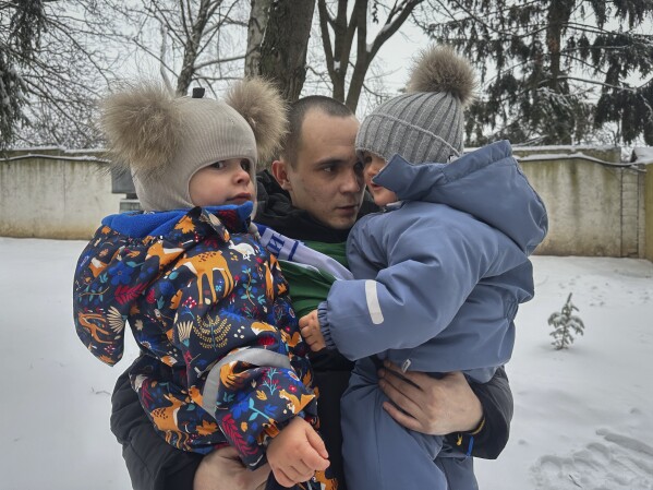 After a prisoner exchange, Artem Dmytryk hugs his 2-year-old son, Timur, right, and a nephew in Kyiv, Ukraine, Feb. 9, 2024. (AP Photo/Vasilisa Stepanenko)