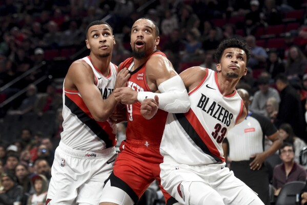 Portland Trail Blazers forward Kris Murray, left, and forward Toumani Camara, right, battle for position under the basket with Houston Rockets forward Dillon Brooks, center, during the first half of an NBA basketball game in Portland, Ore., Friday, March 8, 2024. (AP Photo/Steve Dykes)
