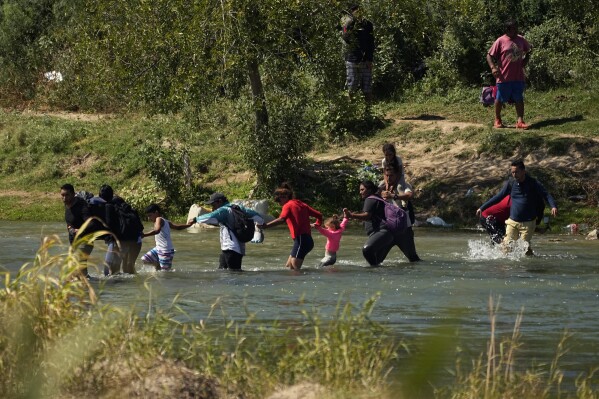 Migrantes cruzan de la mano el Río Bravo desde México a Estados Unidos, el 21 de septiembre de 2023, en Eagle Pass, Texas. (AP Foto/Eric Gay)