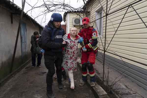 Associated Press photographer Evgeniy Maloletka helps a paramedic to transport a woman injured during shelling in Mariupol, eastern Ukraine, Wednesday, March 2, 2022. (AP Photo/Mstyslav Chernov) 