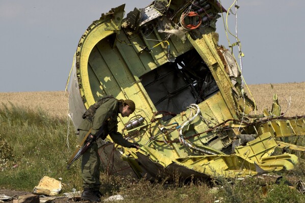 A pro-Russian rebel touches the MH17 wreckage at the crash site of Malaysia Airlines Flight 17, near the village of Hrabove, eastern Ukraine, on July 22, 2014. (AP Photo/Vadim Ghirda, File)