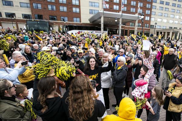 Iowa guard Caitlin Clark, center, high-fives fans surrounding the team bus as the Iowa women's college basketball team returns home Monday, April 3, 2023, in Coralville, Iowa, after playing against LSU in the NCAA National Championship, Sunday. (Joseph Cress/Iowa City Press-Citizen via AP)