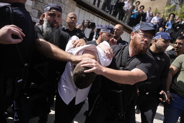 Israeli police detain a suspected attacker in an apparent car ramming that wounded three people on the eve of the Jewish holiday of Passover, in Jerusalem, Monday, April 22, 2024. Israeli police said they have arrested two people after a car slammed into pedestrians in Jerusalem on Monday, lightly wounding three. (AP Photo/Ohad Zwigenberg)