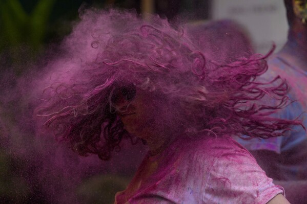 A girl shakes her head, smeared with colored powder, as people celebrate Holi, the festival of colors, in Mumbai, India, Monday, March 25, 2024. (AP Photo/Rafiq Maqbool)