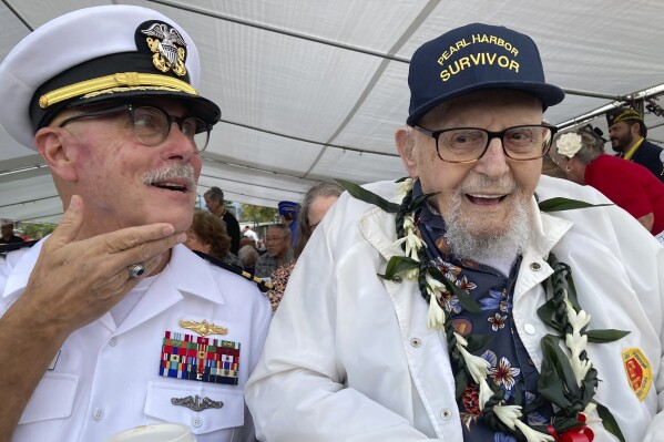 FILE - Ira Schaub, right, who survived the attack on Pearl Harbor as a sailor on the USS Dobbin, speaks to reporters while sitting next to her son, a retired Navy commander.  Carl Schaub, Dec. 7, 2022, in Pearl Harbor, Hawaii.  (AP Photo/Audrey McEvoy, File)