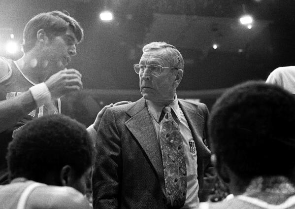 CORRECTS THE LOCATION TO CHICAGO AND NOT LOS ANGELES AS ORIGINALLY SENT - FILE - UCLA coach John Wooden listens to Greg Lee, left, during a timeout in the team's NCAA college basketball game against Iowa in January 1974 in Chicago. Lee, who helped UCLA to consecutive national championships in 1972 and '73 as a starting guard under Wooden, has died. He was 70. Lee died at a San Diego hospital Wednesday, Sept. 21, 2022, from an infection related to an immune disorder, the university said Thursday after being informed by his wife, Lisa. (AP Photo, File)
