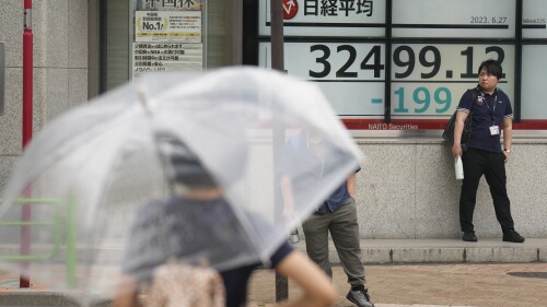 Pedestrians wait at a traffic intersection near monitors showing Japan's Nikkei 225 index at a securities firm in Tokyo, Tuesday, June 27, 2023. Asian stock markets were mixed on Tuesday after Wall Street fell after its latest rally.  (AP Photo/Hiro Komae)