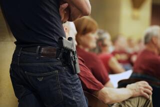 FILE - A Glock handgun is holstered on the side of Kristopher Kranz of Bloomington, Minn., as he listens during public testimony on Aug. 20, 2013, in St. Paul, Minn. A federal court ruling that a Minnesota law prohibiting 18-to-20-year-olds from obtaining permits to carry handguns in public is unconstitutional remained on hold Monday, April 3, 2023, while the state pursues a potential appeal. (AP Photo/Jim Mone, File)
