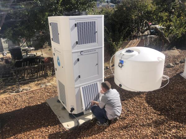 Ted Bowman, design engineer with Tsunami Products, installs a unit in homeowner Don Johnson's backyard in Benicia, Calif., Sept. 28, 2021. The recent invention can make water out of the air and in parched California, some homeowners are already buying the pricey devices. The air-to-water systems work like air conditioners by using coils to chill air, then collect water drops in a basin. (AP Photo/Haven Daily)