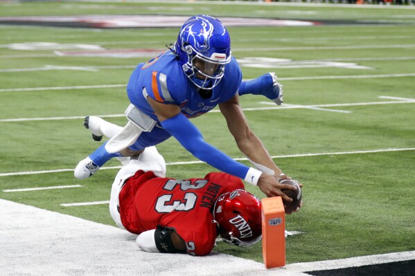 Boise State quarterback Taylen Green (10) dives over UNLV defensive back Quentin Moten (23) for a touchdown during the first half of the Mountain West championship NCAA college football game Saturday, Dec. 2, 2023, in Las Vegas. (Steve Marcus/Las Vegas Sun via AP)
