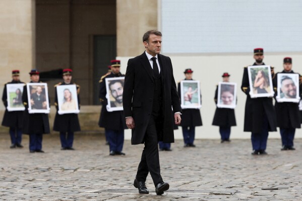 French President Emmanuel Macron walks past French Republican Guards who hold portraits of the French victims of the Oct.7 2023 Hamas' attack, during a ceremony at the Invalides monument, Wednesday, Feb.7, 2024. France is paying tribute to French victims of Hamas' Oct. 7 attack, in a national ceremony led by President Emmanuel Macron four months after the deadly assault in Israel that killed some 1,200 people, mostly civilians, and saw around 250 abducted.(Gonzalo Fuentes/Pool via AP)