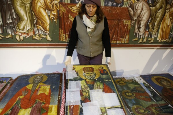 A museum worker displays an icon returned from Albania at the National museum in Skopje, North Macedonia, late Friday, Dec. 15, 2023. Albania on Friday returned 20 icons to neighboring North Macedonia that were stolen a decade ago. (AP Photo/Boris Grdanoski)