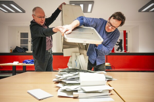 Poll workers empty the ballot boxes at polling station 317 in the Carl von Ossietzky-Gymnasium during the vote count in Berlin, Sunday Feb. 11, 2024. A partial rerun of Germany's 2021 election in Berlin brought a decline in support for the governing parties and cost one of them a seat in parliament, but led to no significant overall change, official results showed Monday. (Soeren Stache/dpa via AP)