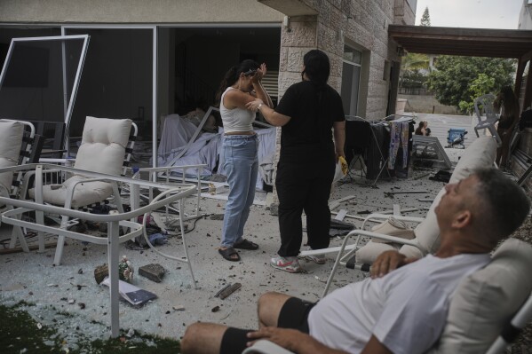 Residents react after their home was struck by a missile launched from Iran, in Rishon Lezion, Israel, on Saturday, June 14, 2025. (AP Photo/Ohad Zwigenberg)