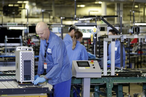 FILE - In this Nov. 20, 2019, file photo workers assemble Apple products at an Apple manufacturing plant in Austin, Texas.  As state and federal leaders tussle over when and how fast to “reopen” the U.S. economy amid the coronavirus pandemic, some corporations are taking the first steps toward bringing their employees back to work.  (AP Photo/ Evan Vucci, File)