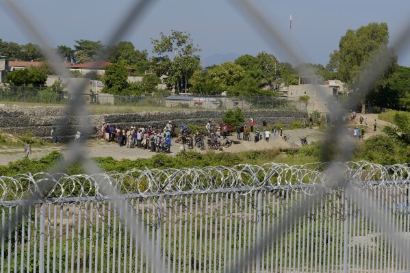 People from Juana Mendez, on the Haitian side of the border, wait in vain to be allowed to cross into Dajabon, Dominican Republic, Wednesday, Oct. 11, 2023. The Dominican Republic partially reopened its border with Haiti on Wednesday to limited commercial activity nearly a month after shuttering the frontier in a continuing spat over the construction of a canal targeting water from a shared river. (AP Photo/Ricardo Hernandez)