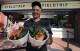 FILE - This Aug. 30, 2019 photo shows chef JJ Johnson posing with two signature rice bowls, one salmon and one vegetable, outside his Field Trip counter-service restaurant kiosk on the food court at the US Open tennis championships in New York. Johnson's new cookbook "The Simple Art of Rice: Recipes from Around the World for the Heart of Your Table," a book co-authored with Danica Novgorodoff, celebrates rice's versatility. (AP Photo/Charles Krupa, File)