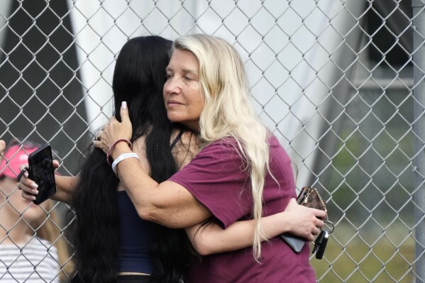 Former special education teacher at Marjory Stoneman Douglas High School, Joanne Wallace, right, hugs another onlooker as they watch crews demolish a building at the school, Friday, June 14, 2024, where 17 people died in a 2018 mass shooting in Parkland, Fla. (AP Photo/Wilfredo Lee)