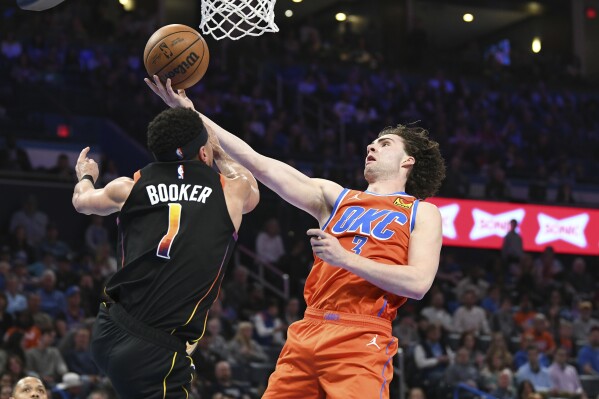 Oklahoma City Thunder guard Josh Giddey (3) shoots against Phoenix Suns iguard Devin Booker (1) during the second half of an NBA basketball game Friday, March 29, 2024, in Oklahoma City. (AP Photo/Kyle Phillips)