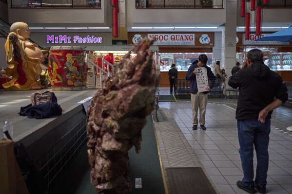Erik Nguyen, a volunteer and UCLA student, holds a vision chart for a participant during a Vietnamese Community Health Project event at Asian Garden Mall in the Little Saigon neighborhood of Westminster, Calif., Saturday, April 26, 2025. (AP Photo/Jae C. Hong)