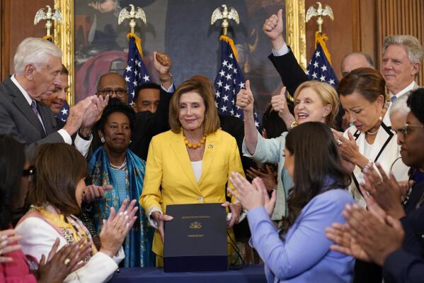 House Speaker Nancy Pelosi of Calif., surrounded by House Democrats, poses after signing the Inflation Reduction Act of 2022 during a bill enrollment ceremony on Capitol Hill in Washington, Friday, Aug. 12, 2022. (AP Photo/Susan Walsh)