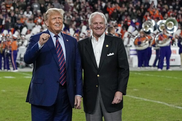 Republican presidential candidate and former President Donald Trump gestures with South Carolina Gov. Henry McMaster during halftime in an NCAA college football game between the University of South Carolina and Clemson Saturday, Nov. 25, 2023, in Columbia, S.C. (AP Photo/Chris Carlson)