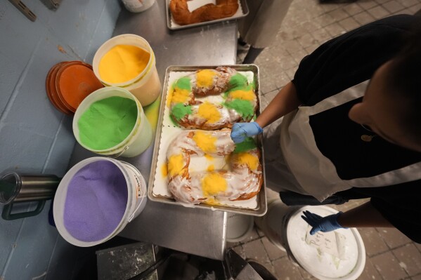 Lawren DiBella sprinkles colored sugar onto king cakes at Haydel's Bakery in Jefferson Parish, La., Wednesday, Jan. 31, 2024. (AP Photo/Gerald Herbert)