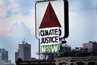 CORRECTS PHRASE IN CAPTION TO CLIMATE JUSTICE NOW INSTEAD OF CLIMATE CHANGE NOW- Members of an environmental group hang a banner that reads “CLIMATE JUSTICE NOW” on the iconic Citgo sign near Boston's Fenway Park in Kenmore Square on Monday, Aug. 8, 2020, in Boston. The group unfurled the banner Monday evening as the Red Sox began their game against the Tampa Bay Rays at Fenway. A spokesman for the group, Extinction Rebellion Boston, told The Boston Globe that it was hoping to bring attention to environmental issues. (Jim Davis/The Boston Globe via AP)