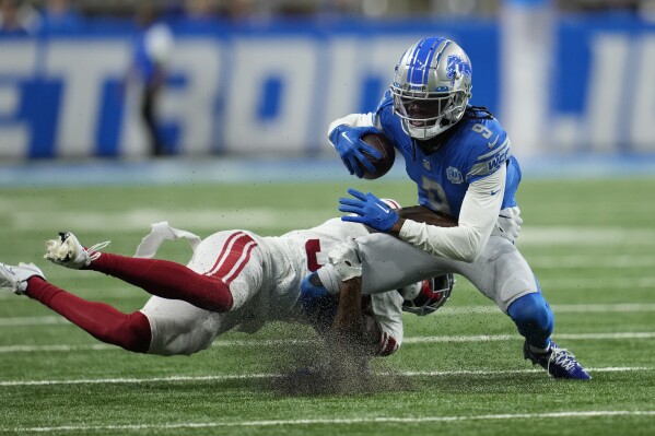 New York Giants cornerback Tre Hawkins III tackles Detroit Lions wide receiver Jameson Williams (9) during the first half of an NFL preseason football game, Friday, Aug. 11, 2023, in Detroit. (AP Photo/Paul Sancya)