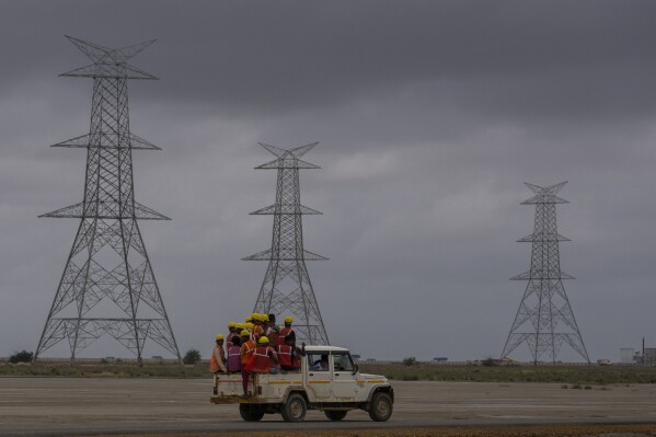 Workers travels in a vehicle toward the construction site of Adani Green Energy Limited's Renewable Energy Park in the salt desert of Karim Shahi village, near Khavda, Bhuj district near the India-Pakistan border in the western state of Gujarat, India, Thursday, Sept. 21, 2023. India is developing a 30 gigawatt hybrid — wind and solar — renewable energy project on one of the largest salt deserts in the world. (AP Photo/Rafiq Maqbool)