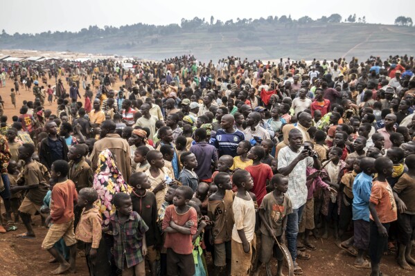 FILE - People displaced by conflict wait for the arrival of United Nations Under-Secretary-General for Peace Operations Jean Pierre Lacroix in Bunia, eastern Congo, Tuesday, Feb. 22, 2022. The United Nations migration agency says a record 6.9 million people have been displaced by conflict across Congo, making it one of the world’s largest displacement and humanitarian crises. The International Organization for Migration says the decadeslong conflict has been the primar(AP Photo/Moses Sawasawa, File)