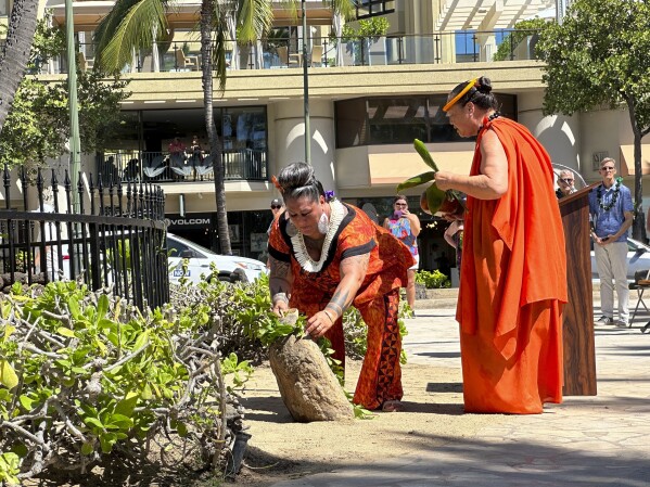Hinaleimoana Wong-Kalu, left, and Charlani Kalama, both kumu, or master teachers, participate in a blessing ceremony for a new plaque for the Kapaemahu stones in Honolulu on Tuesday, Oct. 24, 2023. Honolulu officials introduced a new interpretive plaque for four large boulders in the center of Waikiki that honor Taihitian healers of dual male and female spirit who visited Oahu some 500 years ago. (AP Photo/Audrey McAvoy)