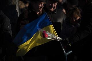 La gente asiste a una ceremonia para conmemorar el aniversario de la retirada de las tropas soviéticas de Afganistán en la ciudad de Kiev, Ucrania, el martes 15 de febrero de 2022. (AP Foto/Emilio Morenatti)