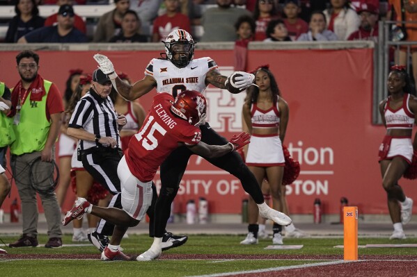 Oklahoma State running back Ollie Gordon II (0) is forced out of bounds by Houston defensive back Malik Fleming (15) during the second half of an NCAA college football game Saturday, Nov. 18, 2023, in Houston. Oklahoma State won 43-30. (AP Photo/David J. Phillip)