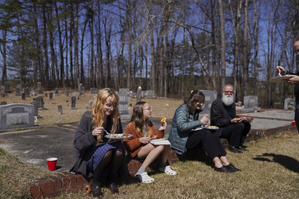 Sacred Harp singers sit among the headstones at Holly Springs Primitive Baptist Church for a midday potluck in Bremen, Ga., on Saturday, March 22, 2025. (AP Photo/Jessie Wardarski)