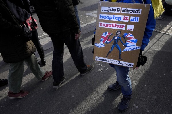 A demonstrator holds a banner calling for a general election, in Westminster in London, Jan. 24, 2024. (AP Photo/Kirsty Wigglesworth)