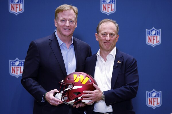 NFL Commissioner Roger Goodell presents new Washington Commanders owner Josh Harris with a team helmet after a special meeting to vote on approval of the sale of the team, Thursday, July 20, 2023, in Bloomington Minn. (AP Photo/Bruce Kluckhohn)