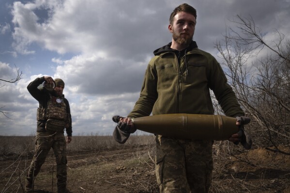 FILE - Ukrainian soldiers carry shells to fire at Russian positions on the front line, near the city of Bakhmut, in Ukraine's Donetsk region, on March 25, 2024. Approval by the U.S. House of a $61 billion package for Ukraine puts the country a step closer to getting an infusion of new firepower. But the clock is ticking. Russia is using all its might to achieve its most significant gains since the invasion by a May 9 deadline. (AP Photo/Efrem Lukatsky, File)