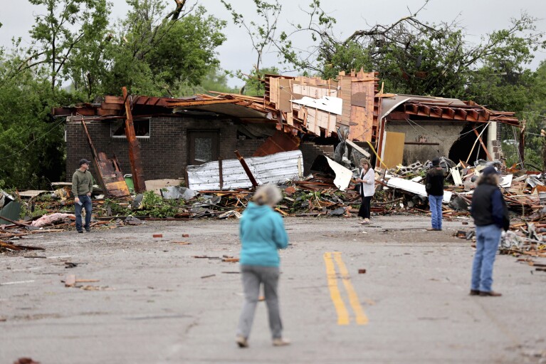 As pessoas observam os danos do tornado depois que fortes tempestades atingiram Sulphur, Oklahoma, domingo, 28 de abril de 2024.  (AP via Brian Terry/The Oklahoman)