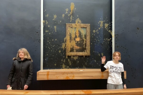 In this grab taken from video, activists react after throwing soup at the glass protecting the Mona Lisa, at the Louvre Museum, Paris, Sunday. Jan. 28, 2024, shouting slogans advocating for a sustainable food system. It comes as French farmers have been protesting for days across the country against several issues, including low wages. (AP Photo/Clement Lanot)