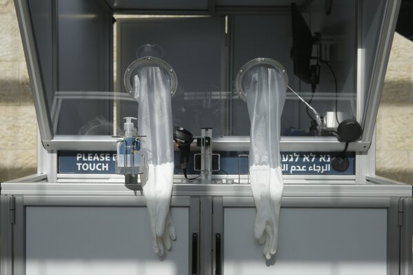 Gloves hang from a booth at a new on-site COVID-19 testing facility at Tel Aviv International Airport in Israel, Monday, Nov. 9, 2020. (AP Photo/Maya Alleruzzo)