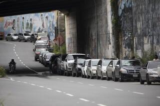 FILE - In this Sept 8, 2020 file photo, vehicles line up near a gas station to fill their tanks in Caracas, Venezuela. Maritime safety mechanisms have become a powerful mechanism for tracking ships engaged in rogue activities like transporting sanctioned crude oil to and from places under U.S. or international sanctions like Venezuela. (AP Photo/Ariana Cubillos, File)