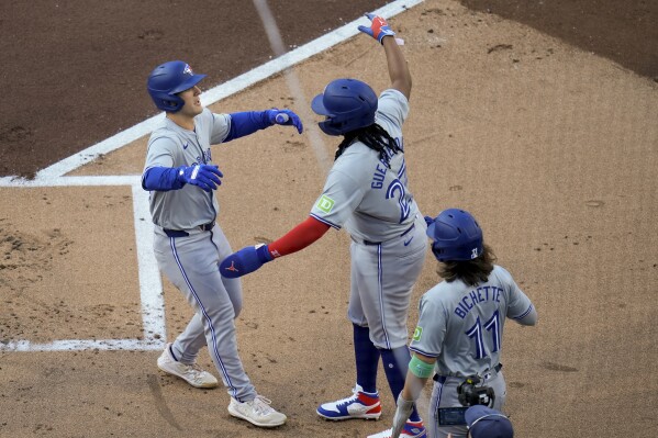 Toronto Blue Jays' Daulton Varsho, left, celebrates with teammates Vladimir Guerrero Jr., center, and Bo Bichette, after hitting a three-run home run during the first inning of a baseball game against the San Diego Padres, Saturday, April 20, 2024, in San Diego. (AP Photo/Gregory Bull)
