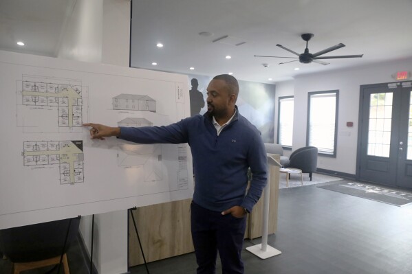 Veterans Empowerment Organization CEO Tony Kimbrough points at design plans for a two-story building that will house 20 formerly homeless veterans, Tuesday, Oct. 31, 2023 in Atlanta. The Atlanta-based nonprofit houses dozens of veterans and helps put them on a path toward employment and housing independence. (AP Photo/R.J. Rico)