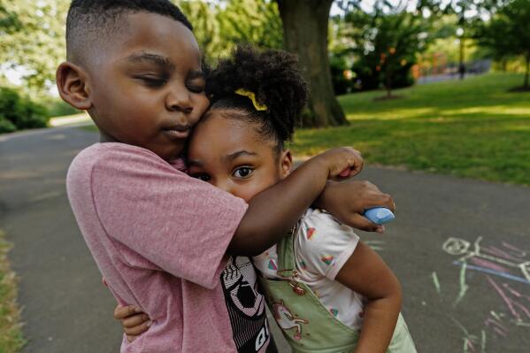 Zavion Guzman hugs his sister Jazzmyn while playing Wednesday, June 30, 2021, in Belleville, N.J. Lunisol Guzman adopted the two as babies but died last year from COVID-19 along with her partner at the start of the violent first wave of the pandemic in the U.S. Northeast. The children's older sisters now care for them. (AP Photo/Mary Altaffer)