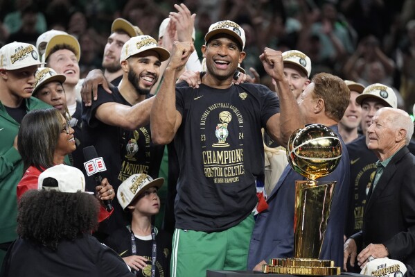 Boston Celtics center Al Horford, center, and forward Jayson Tatum, center left, celebrates with teammates near the Larry O'Brien Championship Trophy after the team won the NBA basketball championship with a Game 5 victory over the Dallas Mavericks, Monday, June 17, 2024, in Boston. (AP Photo/Charles Krupa)