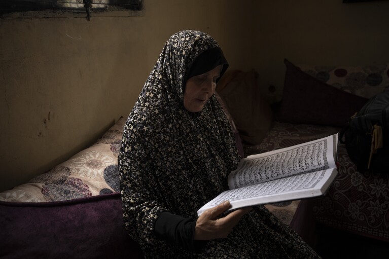 Huda Zaqqout reads from a large copy of the Muslim holy book at her home a few weeks before she is slated to travel to Mecca for the Muslim pilgrimage in Gaza City Wednesday, May 31, 2023. (AP Photo/Fatima Shbair)