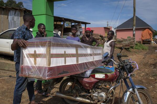 People load a coffin onto the back of a motorcycle to transport it to be used for the burial of an Ebola victim, in the town of Kassanda in Uganda Tuesday, Nov. 1, 2022. Ugandan health officials say they have controlled the spread of a strain of Ebola that has no proven vaccine, but there are pockets of resistance to health measures among some in rural communities where illiteracy is high and restrictions on movement and business activity have left many bitter. (AP Photo/Hajarah Nalwadda)