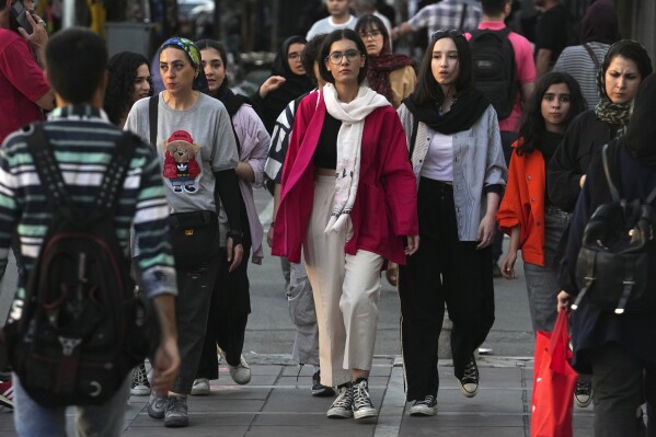 FILE - Iranian women, some without wearing their mandatory Islamic headscarves, walk in downtown Tehran, Iran, Saturday, Sept. 9, 2023. Iran's parliament on Wednesday, Sept. 20, 2023, approved a bill to impose heavier penalties on women who refuse to wear the mandatory Islamic headscarf in public and those who support them. The move came just days after the anniversary of the death of Mahsa Amini, a 22-year-old woman who had been detained by the morality police for violating the country's dress code. (AP Photo/Vahid Salemi, File)